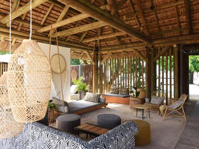 Offener, gemütlicher Lounge-Bereich mit Holzstruktur und Korbmöbeln in einem tropischen Hotel.