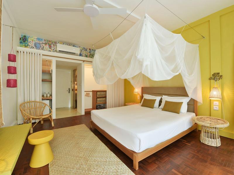Cozy hotel room with canopy bed, yellow walls, and modern decor.