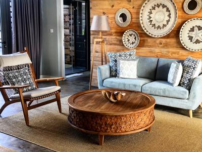 Gemütliches Wohnzimmer mit Holzwänden, blauer Couch, Holzstuhl und rundem Holz-Couchtisch.