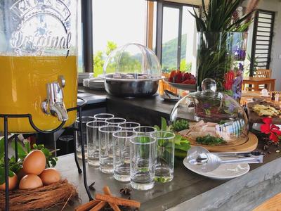 Frühstücksbereich mit Saftspender, Eiern, Gläsern, Gebäck und Gewürzen auf grauer Arbeitsfläche.