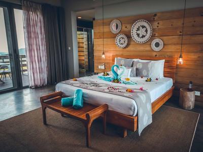 Modernes Schlafzimmer mit Holzverkleidung, Doppelbett, Wanduhren und warmem Licht.