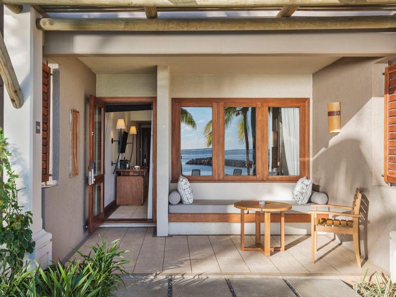 Gemütliche Terrasse mit Sitzbank, Tisch und Ausblick auf das Meer bei sonnigem Wetter.