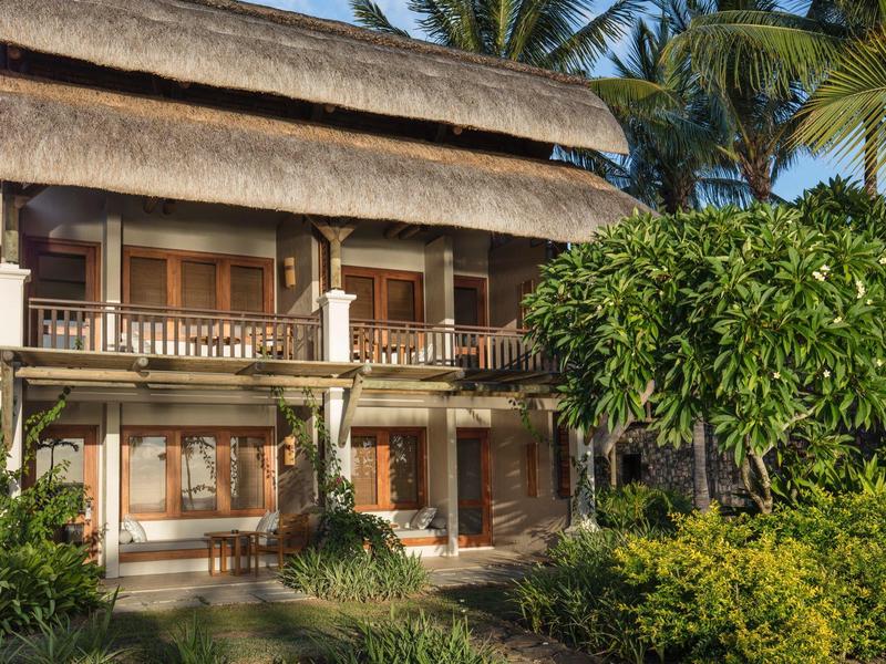 Traditionelles zweistöckiges Hotelgebäude mit Strohdach und tropischem Garten in sonniger Umgebung