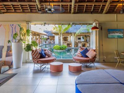 Otwarta przestrzeń lounge z miejscami do siedzenia z widokiem na ogród i basen w hotelu tropikalnym.