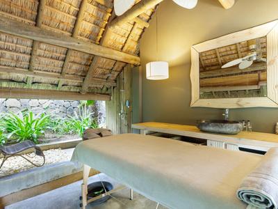 Jasny pokój do zabiegów wellness z bambusowymi sufitami i widokiem na ogród.