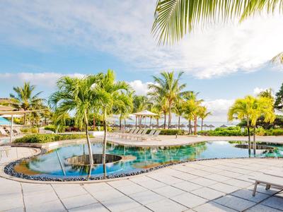 Moderner Swimmingpool mit Palmen und Sitzgelegenheiten in tropischer Hotelanlage.