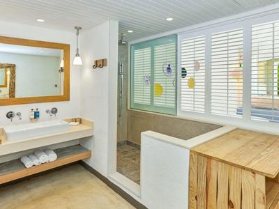 Nowoczesna łazienka z podwójną umywalką, dużym lustrem i prysznicem za okiennicami.