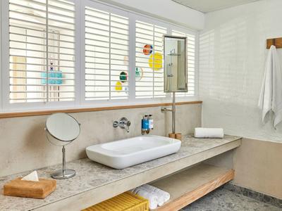 Nowoczesna łazienka z umywalką na blacie i dużymi oknami z żaluzjami.