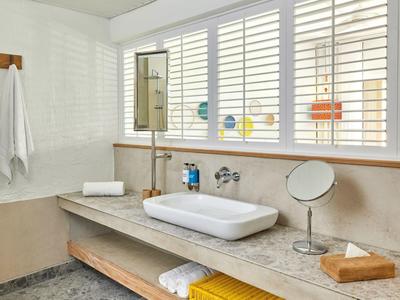 Nowoczesna łazienka z dużą umywalką, lustrem i żółtym ręcznikiem pod umywalką.