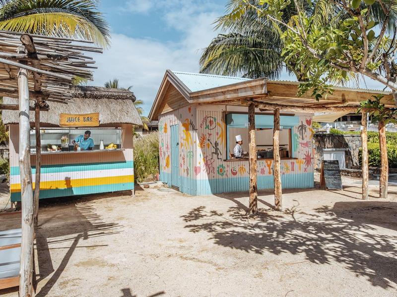 Mała tropikalna restauracja z barem i kolorowymi ścianami pod palmami w miejscu wakacyjnym