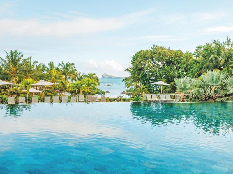 Basen infinity z tropikalnym krajobrazem, palmami i widokiem na morze.