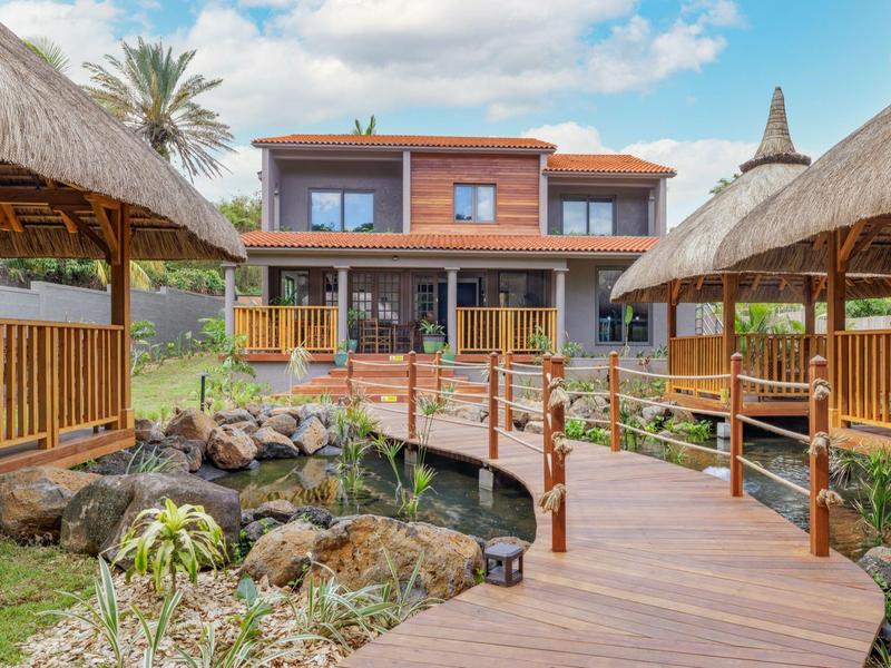 Nowoczesny dwupiętrowy bungalow z drewnianymi chodnikami, drewnianymi altanami i urządzonym ogrodem