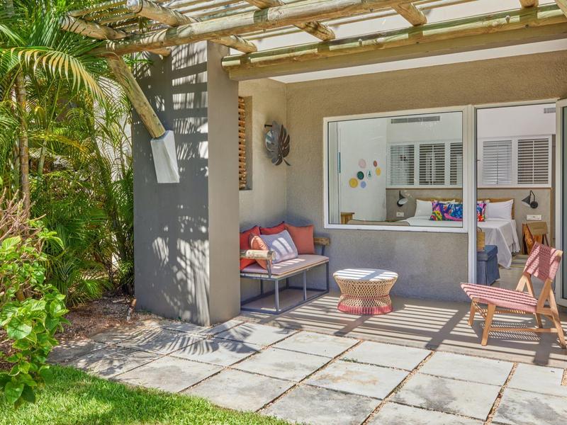 Przytulny taras z miejscami do siedzenia przed pokojem hotelowym, otoczony roślinami.