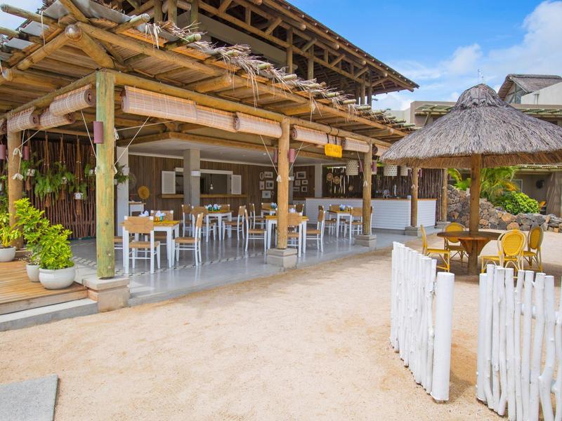 Otwarte nadmorskie restauracja z drewnianymi meblami i piaszczystą podłogą pod niebieskim niebem