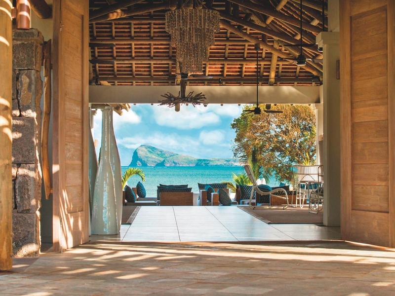 Otwarta przestrzeń z widokiem na taras, ogród i morze pod niebieskim niebem.