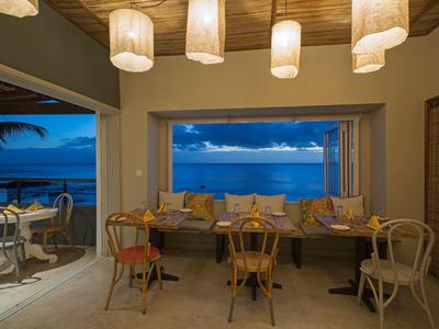 Area interna accogliente di un ristorante con vista sul mare al crepuscolo.