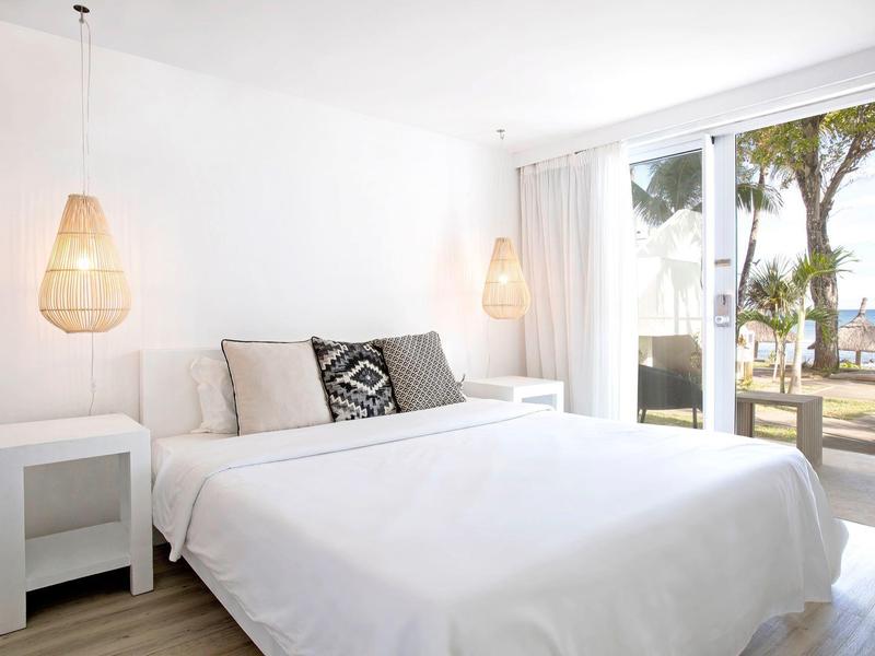 Camera luminosa con letto grande, mobili bianchi e balcone con vista sul mare.