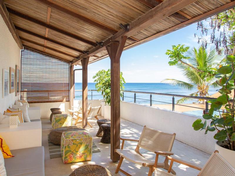 Terrazza coperta con posti a sedere e vista mare in una giornata di sole.