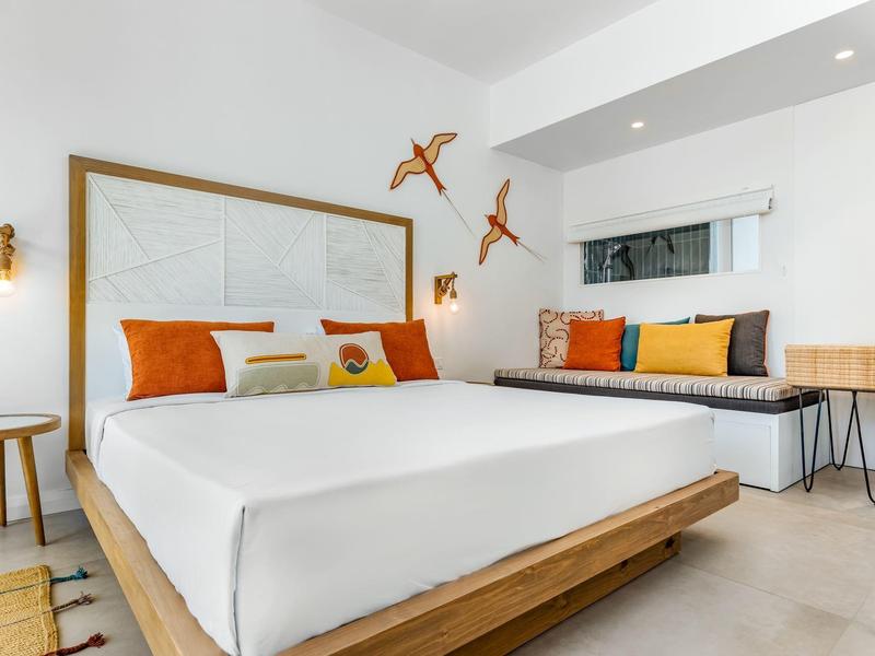 Modern hotel room with large bed, colorful pillows, and stylish wall decorations.