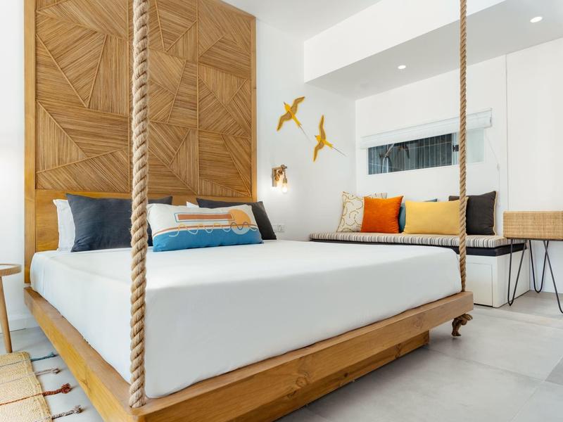 Bright bedroom with floating wooden frame bed and colorful pillows.