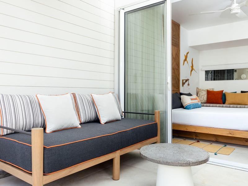 Modern seating area with cozy sofa and view into a bedroom with a double bed.