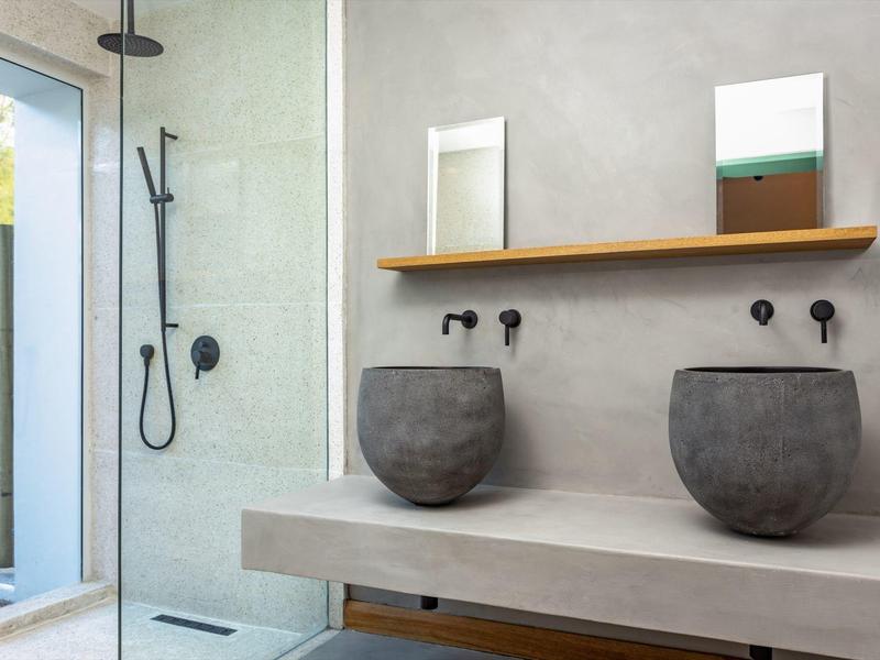 Modern bathroom with two round sinks, black fixtures, and a glass shower.