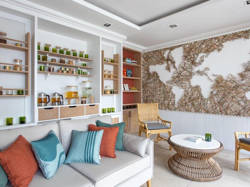 Modern lounge area with cozy sofa, world map wall, and shelves filled with plants and accessories.