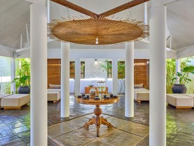 Otevřená, světlá hotelová hala s dekoracemi z ratanu a pohodlnými pohovkami.