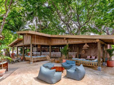 Gemütlicher Outdoor-Loungebereich mit blauen Sitzsäcken und hölzernen Möbeln unter grünen Bäumen.