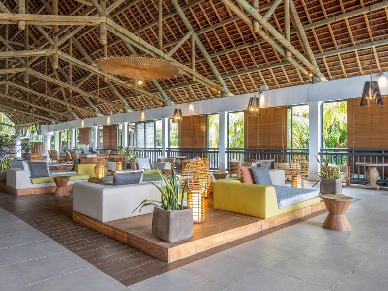 Prostorný otevřený hotelový salonek s vysokými dřevěnými stropy a moderními posezeními.