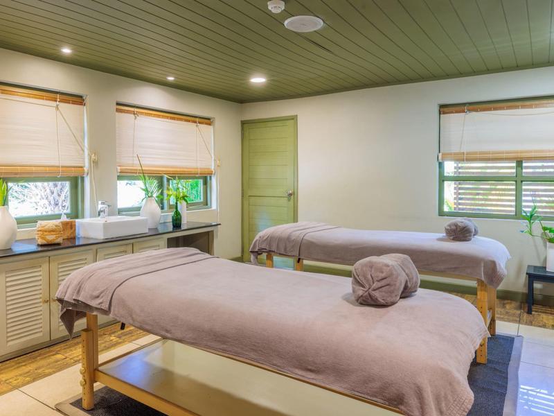 Prosvětlená wellness místnost se dvěma masážními lehátky a velkými okny se žaluziemi.