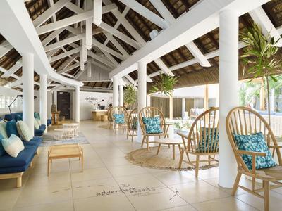 Jasny hol z białymi drewnianymi belkami, meblami z rattanu i niebieskimi poduszkami w tropikalnym hotelu.