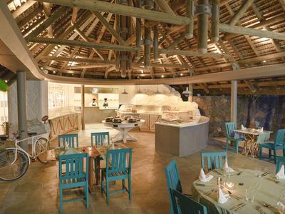 Gemütlicher Gastraum mit Holzdach und blau lackierten Stühlen in einem Restaurant.