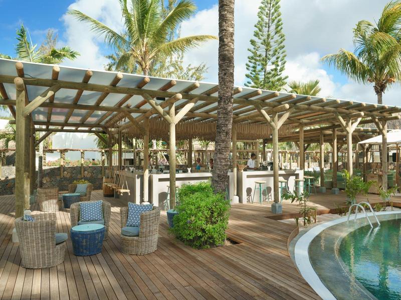 Freizeitbereich mit überdachten Sitzgelegenheiten und Fitnessgeräten neben einem Pool.