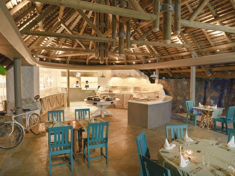 Gemütlicher Gastraum mit Holzdach und blau lackierten Stühlen in einem Restaurant.