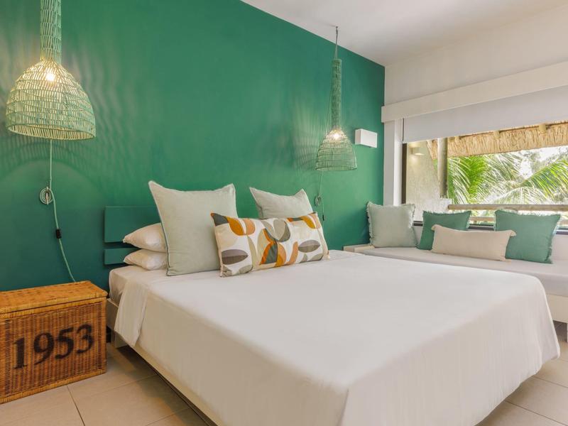 Modernes Schlafzimmer mit grünem Akzent, Doppelbett und gemütlicher Sitzbank am Fenster.