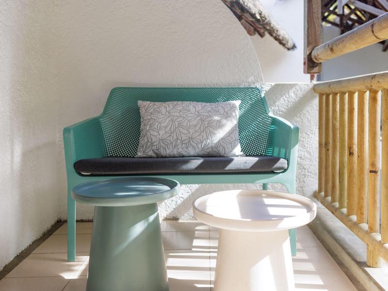 Balkon mit grünem Sessel, zwei modernen Tischen und einem grauen Kissen