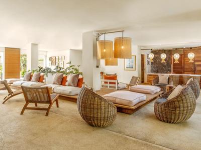 Helle Hotellobby mit moderner Korbmöblierung und Rezeption im Hintergrund.