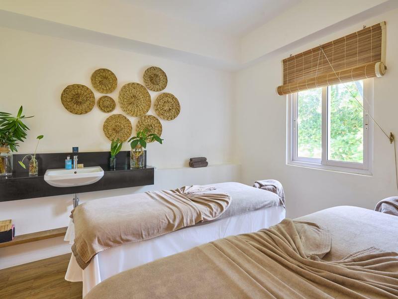 Minimalistická léčebna se dvěma lůžky, dekorativními koši na zdi a velkým oknem.