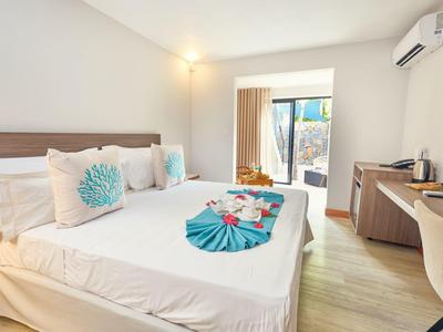 Světý hotelový pokoj s velkou postelí, psacím stolem, klimatizací a přístupem na terasu.