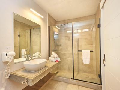 Moderní koupelna se sprchou, umyvadlem a velkým zrcadlem.