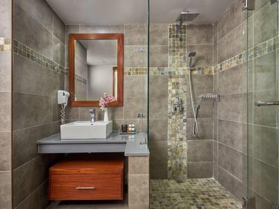 Modernes Badezimmer mit Waschbecken, Holzschrank und begehbarer Dusche mit Glaswand.