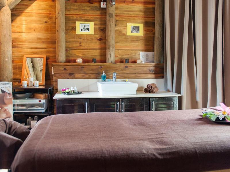 Příjemná ošetřovací místnost s dřevěnými stěnami, masážním stolem a uklidňujícím zařízením.