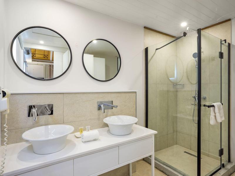Moderní koupelna s dvojumyvadlem, dvěma kulatými zrcadly a sprchovým koutem.
