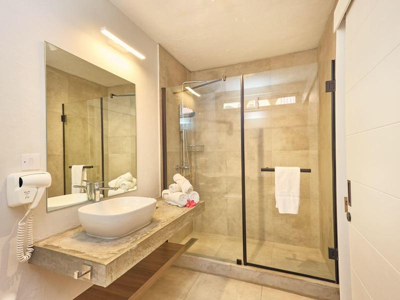 Moderní koupelna se sprchou, umyvadlem a velkým zrcadlem.