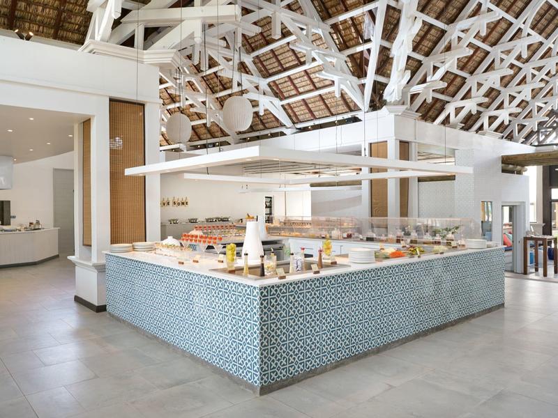 Buffet moderno con varias comidas en un restaurante luminoso y abierto con techo alto.