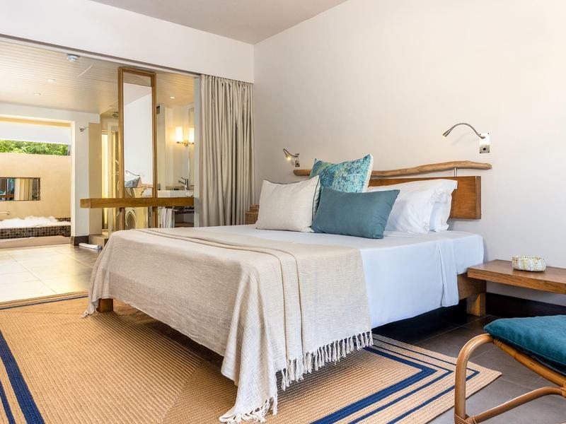 Dormitorio moderno y luminoso con cama grande y acceso a terraza con zona de estar.