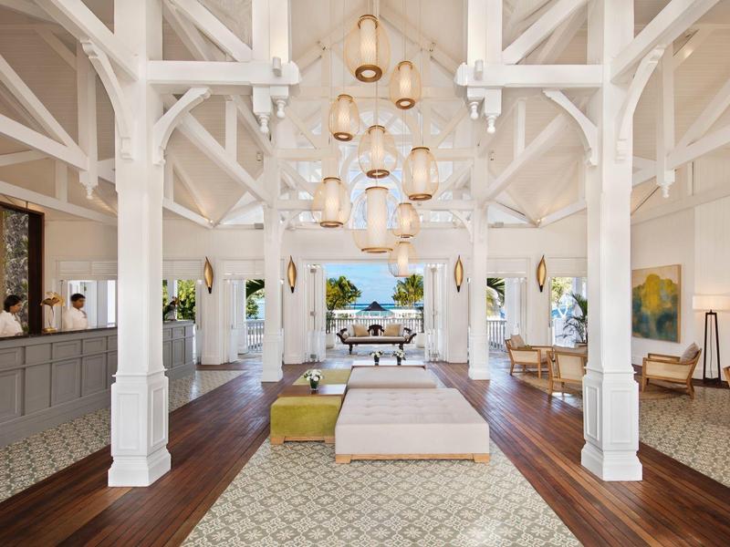 Großer heller Raum mit weiß lackierten Balken, Holzfußboden, Sitzgruppen und modernen Lampen.