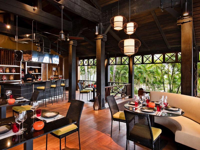 Einladendes Restaurant mit Holz- und Ledermöbeln, runden Laternen und großen Fenstern mit Grünblick.