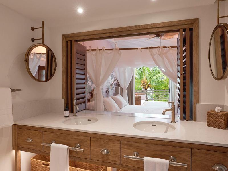 Moderní koupelna se umyvadlem, zrcadly a výhledem na terasu s závěsy.